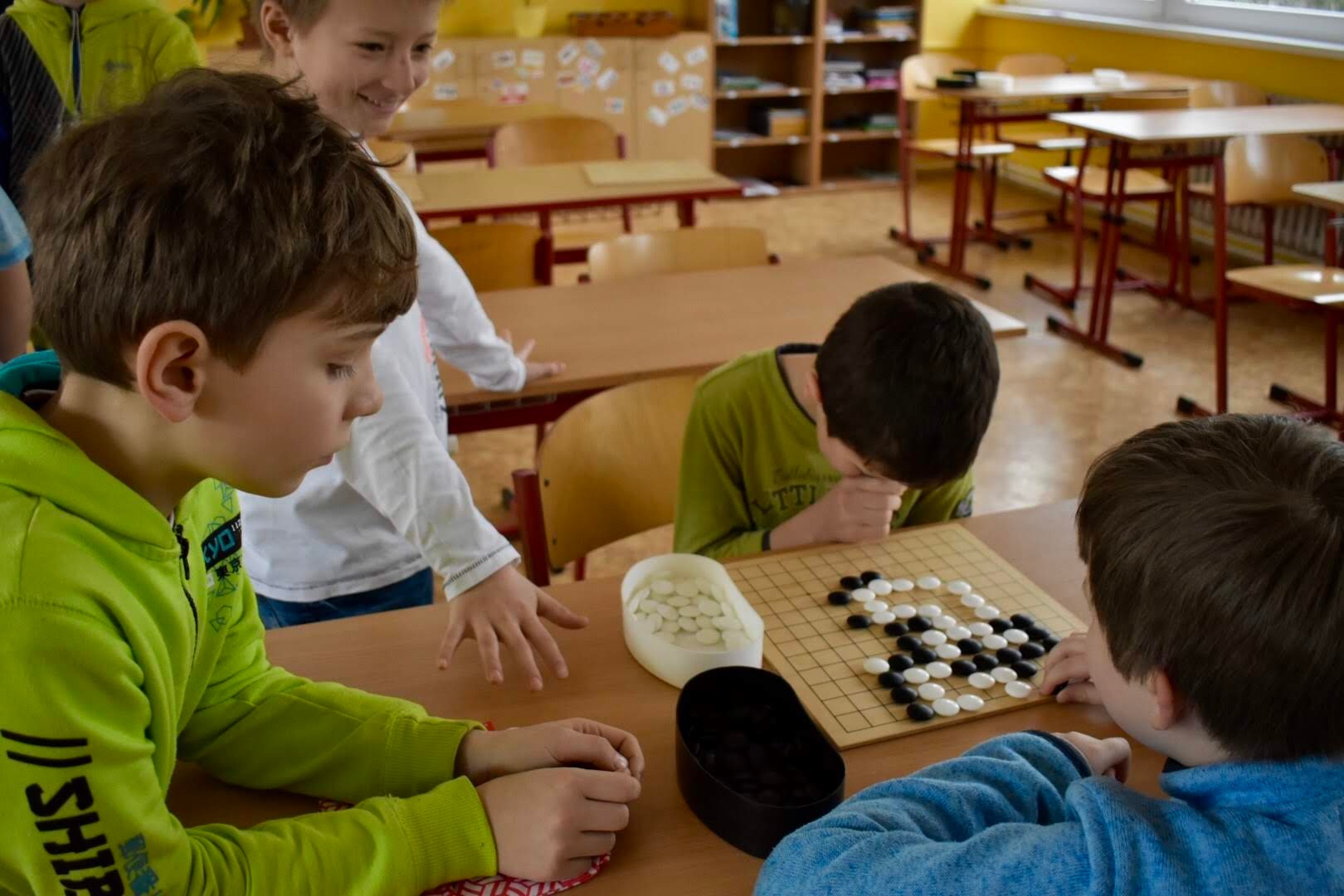 Skupinka dětí nadšeně sleduje partii go